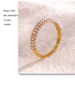Détail d'une bague dorée avec incrustation de demi-perles sur un fond en pierre naturelle