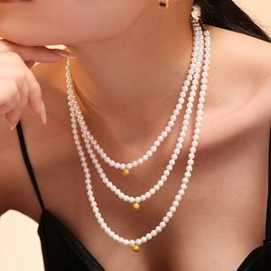 Three-layer baroque pearl necklace with gold sphere charms on female model