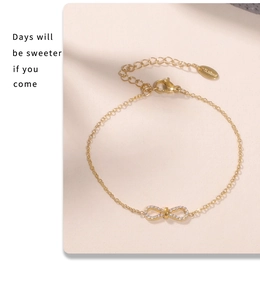 Close-up of gold infinity charm bracelet with micro-pave zircons and S.steel tag