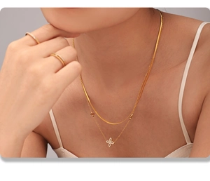 Detail of double-layered gold stainless steel necklace with sparkling clover pendant