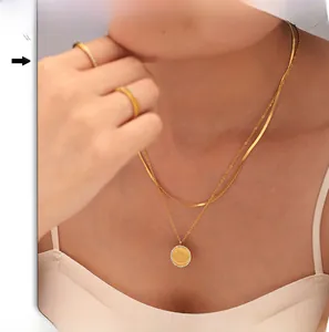 Dettaglio della collana doppia in oro 18K con ciondolo inciso 'Mère Veilleuse' e strass
