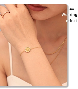 Dettaglio del bracciale dorato con disco di diamanti e incisione Mère Veilleuse raffinata