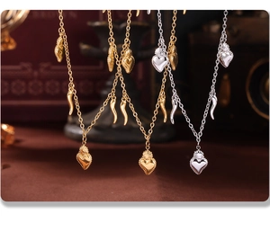 Detail of 18K gold plated sacred heart and cornicello pendants on stainless steel necklace