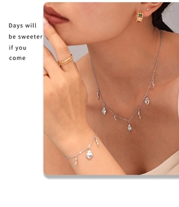 Close-up of silver steel jewelry set featuring heart and horn pendants on a model