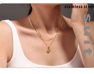 Detalle de collar de doble capa de acero dorado con candado de corazón y colgante turquesa