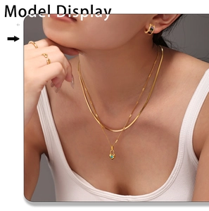 Primer plano de collar dorado de varias capas con colgante de corazón turquesa en modelo