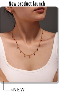 Detail of red bead choker necklace and gold studs worn on a model with 18K gold finish