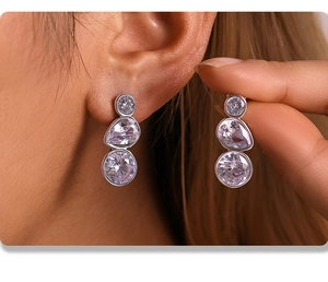 Macro detail of silver drop earrings featuring triple-set sparkling cubic zirconia stones