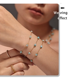 Close-up of golden necklace and bracelet set with light blue stones on a model
