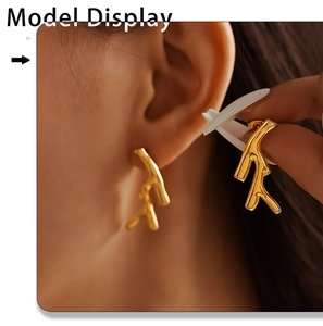 Detail view of golden coral branch earrings showing polished texture on a model