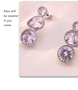 Macro shot of silver drop earrings with three-stone zircon in a linear vertical arrangement