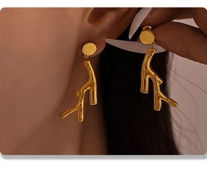 Detailed view of golden branch earrings with a polished PVD finish on an ear model
