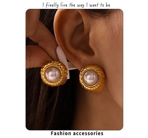 Close-up of 18k gold plated ribbed pearl stud earrings worn by a model in warm light