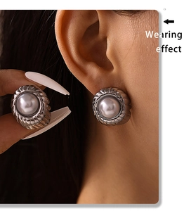 Close-up of a silver pearl stud earring with pleated metal edge on model ear lobe