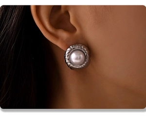 Detailed close-up of a French style pearl stud earring with a silver grooved metal frame