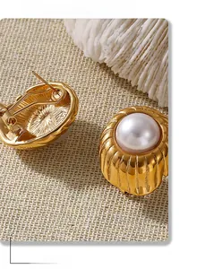 Detail showing the ribbed gold-plated metal and a white pearl on a woven background