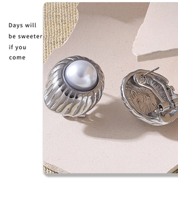 Detail of silver pearl stud earrings with textured metal on a neutral stone display