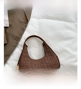 Close-up of brown crocodile texture on a crescent shoulder bag with golden zipper
