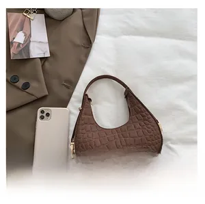 Detail showing the dark brown crocodile embossed texture and golden zipper on the crescent bag