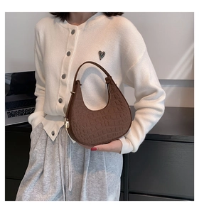Brown crocodile-embossed hobo bag on shoulder showing authentic size and texture