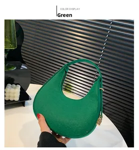 Detail of green crescent bag with felt texture and golden zipper against soft shadows