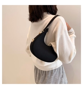 Close-up of black crescent underarm bag with gold hardware worn by a model