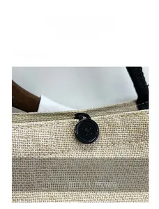 Detail of linen tote bag showing black button closure and textured natural fabric