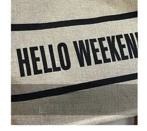 Detailed close-up of a linen tote bag featuring HELLO WEEKEND text and woven texture