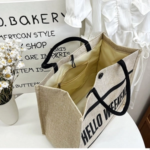 Detailed macro of jute tote bag with HELLO WEEKEND print and black ribbon handles