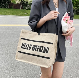 Chic linen tote bag featuring HELLO WEEKEND print with black handles and tulip bouquet