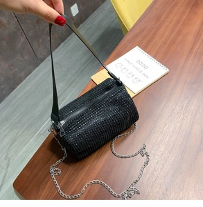 Detail of black rhinestone cylinder bag with silver chain and metal zipper closure