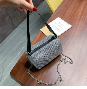 Detail of silver rhinestone cylinder bag with dual metal chain and black wide straps