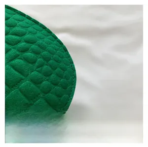 Vue macro d'un sac selle en feutre vert avec texture embossée motif crocodile détaillée