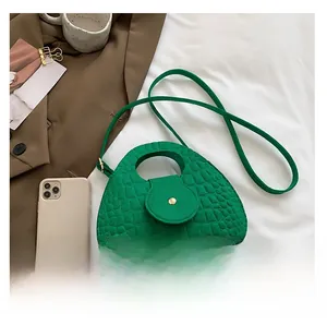 Détail de texture crocodile vert et boucle dorée sur un sac à main hobo élégant