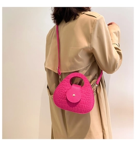 Détail du sac de selle rose fuchsia en relief crocodile avec poignée ronde et bandoulière