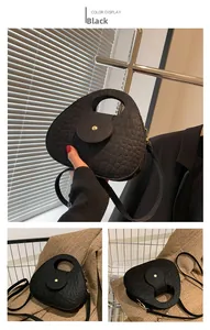 Détail du sac selle noir avec motif crocodile, poignée ronde et boucle métallique