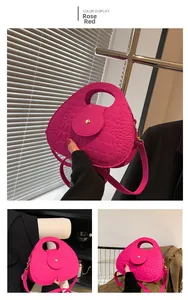 Détail du sac à main rose rouge avec texture crocodile et fermeture à bouton pression métal