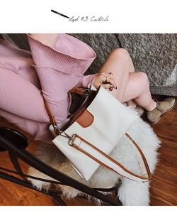 Lifestyle-Foto der zweifarbigen Eimertasche in Beige und Braun mit Model im Strickkleid