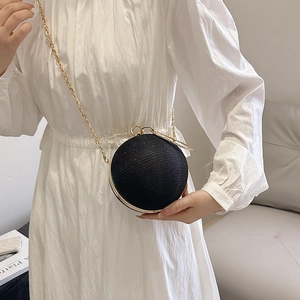 Détail d'un sac de soirée sphérique noir pailleté avec une fine chaîne dorée