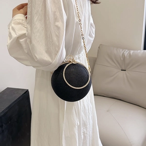 Détail d'un sac de soirée sphérique noir scintillant avec anneaux en métal doré et chaîne