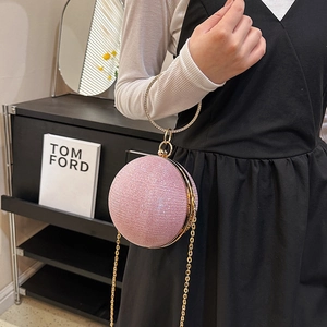 Détail de la pochette sphérique rose avec texture pailletée et poignée anneau dorée