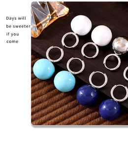 Detailed view of colorful spherical drop earrings set in silver finish on wooden display