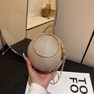 Détail d'un sac de soirée sphérique doré orné de strass avec poignée en anneau