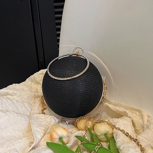 Gros plan d'un sac de soirée sphérique à paillettes noires et poignée en métal strassé