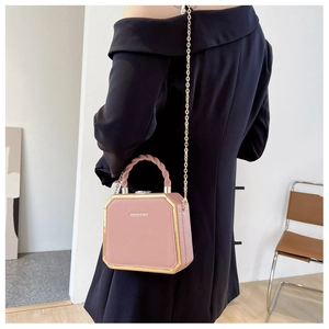 Detail van roze geometrische boxtas met gouden ketting en getextureerd leer