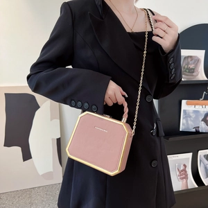 Roze zeshoekige boxtas met gouden ketting en metalen frame gedragen door een model