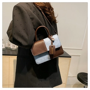 Detail of a brown leather and blue denim patchwork crossbody bag styled with a model