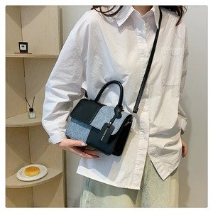 Detail view of contrast color crossbody bag with black leather and blue denim patchwork