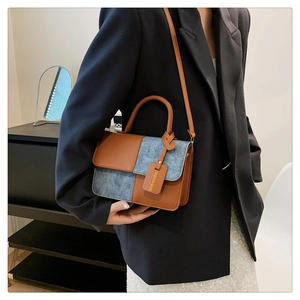 Detail of color-block crossbody bag featuring brown leather and grey denim texture fabric