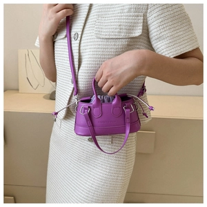 Detail of purple mini shell handbag with drawstring pouch and crossbody strap on model